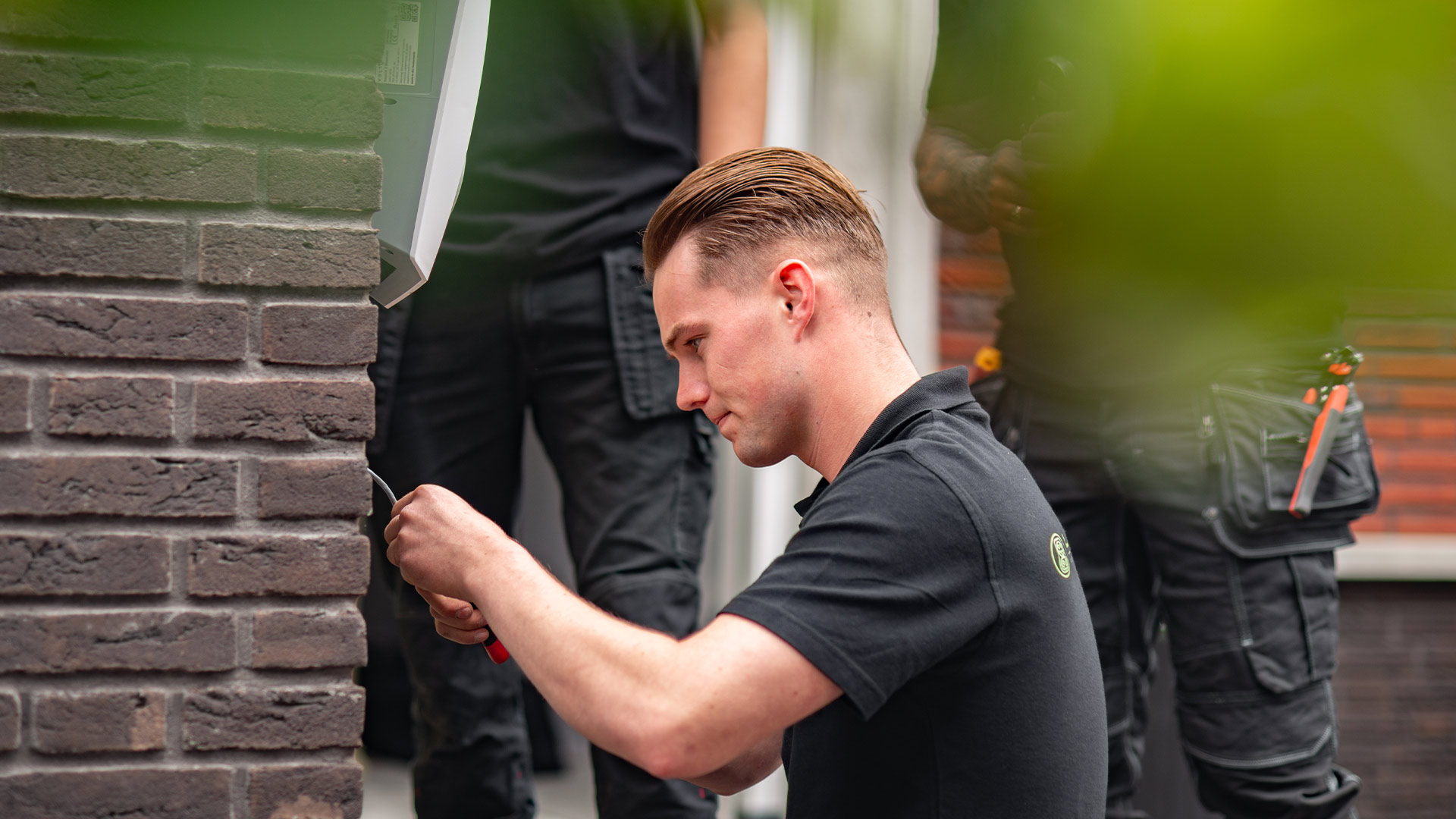Technician installing a Volt Time Source 2S charging station on an exterior wall, close-up of the connections.